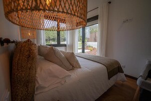 Un dormitorio con cama, ventana y lámpara de mimbre.