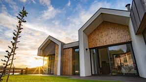 Une maison moderne avec un toit en pente, de grandes fenêtres et une façade en bois.