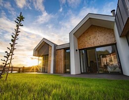 Una casa moderna con techo inclinado, ventanas amplias y fachada de madera.