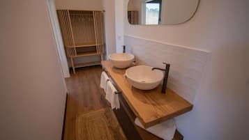 Un baño moderno con dos lavamanos, un mueble de tocador de madera, un perchero para toallas y un espejo grande.