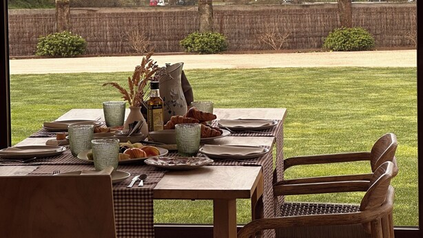 Une table à manger, avec des assiettes, des verres et une bouteille, placée devant un paysage marin.