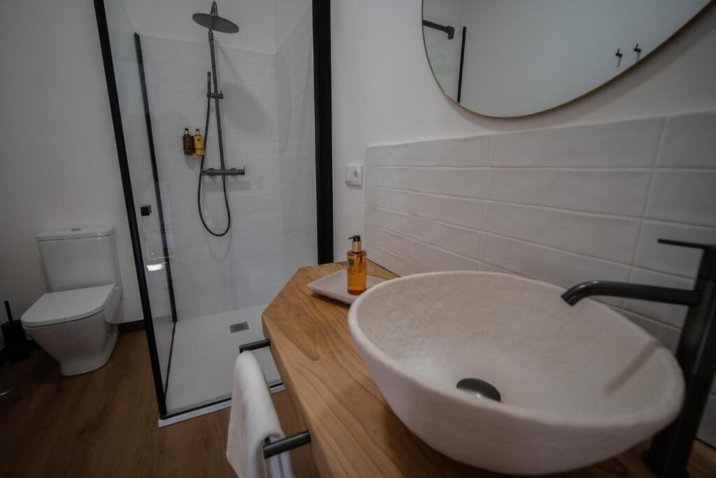 Un baño moderno con ducha envuelta en vidrio, un lavabo blanco y un espejo en la pared.