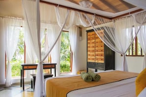 A room with a bed, a wooden cabinet, a table, and a chair.