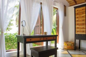 Una habitación con escritorio, espejo, taza y ventana con cortinas.