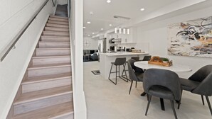 A modern interior with a staircase, a dining area with chairs, a kitchen, and a large abstract painting on the wall. - Luxury Side by Side Lakeview Condos (Leamington)