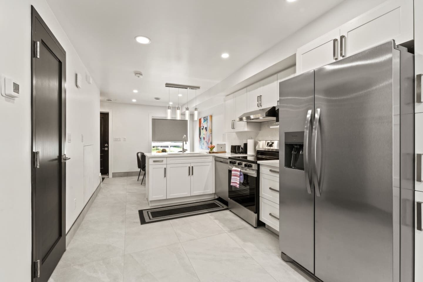A modern kitchen with stainless steel appliances, white cabinetry, and a central island with seating.