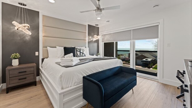 A modern bedroom with a bed, bedside table, and a view of the outside. - Luxury Side by Side Lakeview Condos (Leamington)