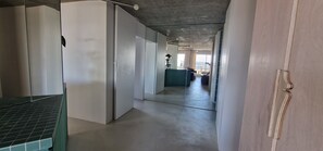 A hallway with a mirrored wall, a green bench, and a view into a room with a large window. - Exceptional rooftop overlooking the sea (La Grande-Motte)