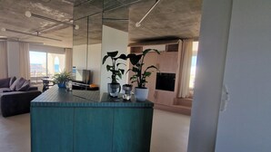 Una cocina moderna con una isla central, plantas en macetas y un amplio ventanal.