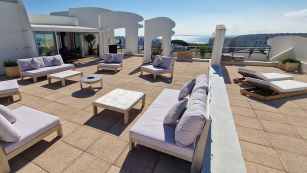 Terraza en la azotea con mobiliario exterior, incluyendo sofás y sillones, y vistas al mar.