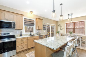 A modern kitchen with wooden cabinets, stainless steel appliances, a large island, and pendant lighting. - Modern New Construction ~ Private Hot Tub, Fire Pit, Gas Grill (Galena)