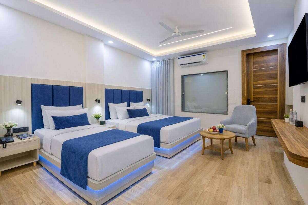 Ein modernes Hotelzimmer mit zwei Betten, einem Schreibtisch, einem Stuhl und einem Fernseher.