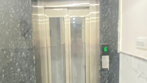 An elevator with a metallic finish, a green emergency button, and a marble floor. - Hotel Air Admire - IGI Airport Delhi (New Delhi)