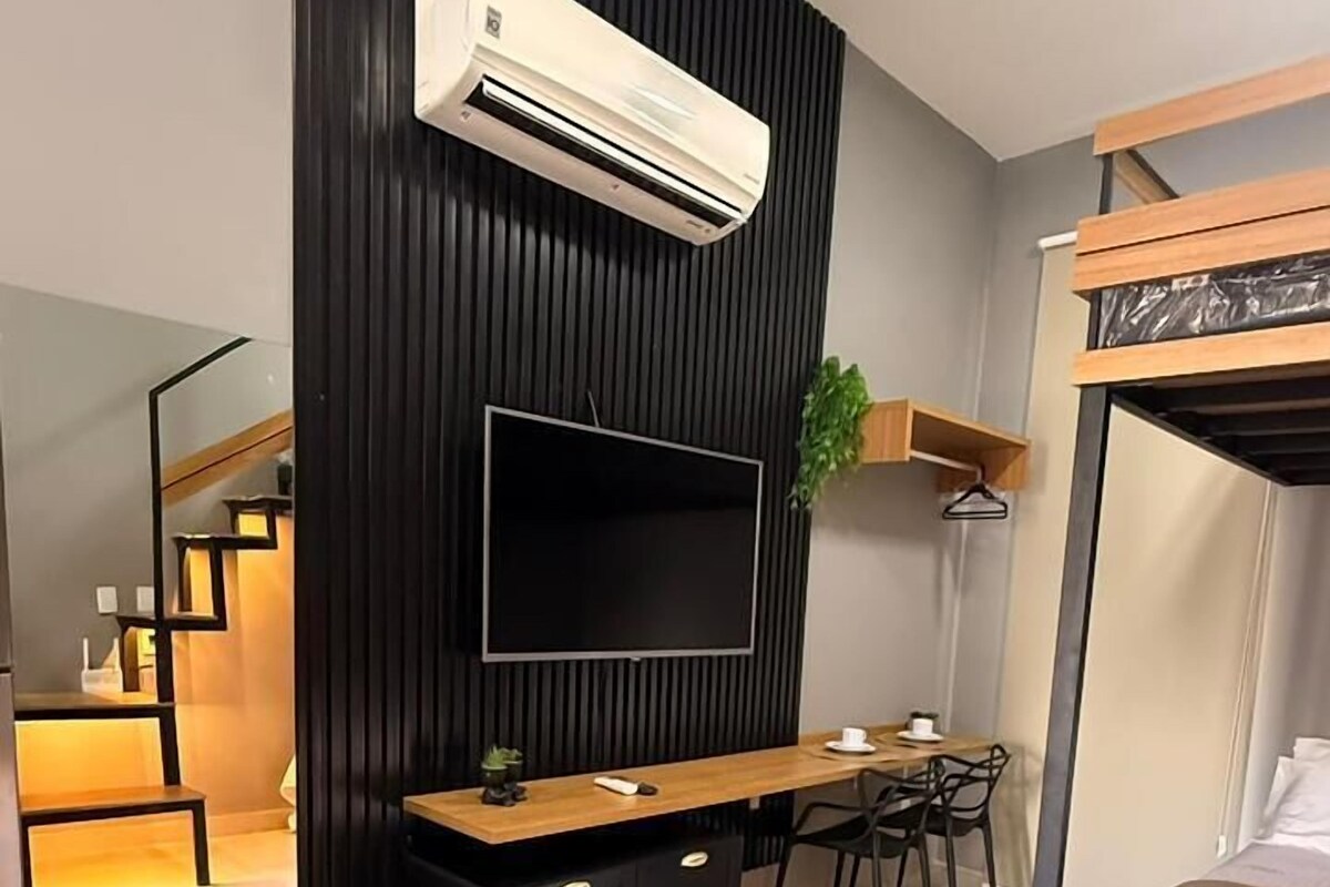 Ein modernes Hotelzimmer mit Fernseher, Etagenbett, Schreibtisch und Stuhl.