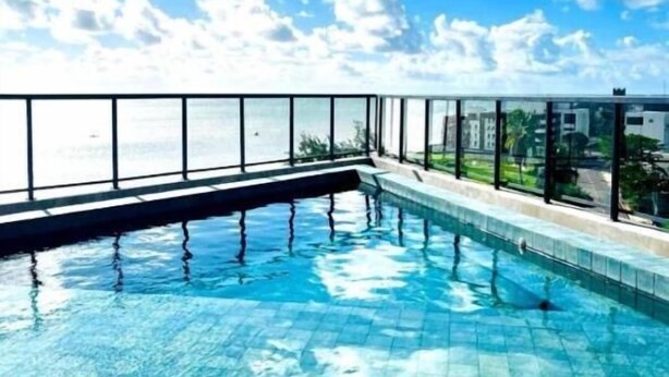 A swimming pool with a glass barrier and a view of the sea. - Beach Flat Sonne (João Pessoa)