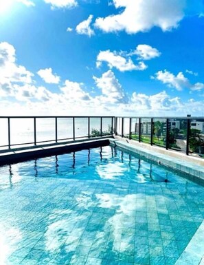 Une piscine dotée d’une paroi en verre et offrant une vue sur la mer.