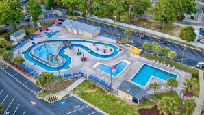 Luchtfoto van een resort met een groot zwembad, een apart gelegen zwembadgedeelte en een parkeerplaats.