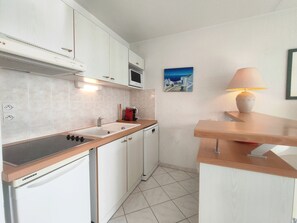 Une cuisine de taille réduite, équipée d’une cuisinière, d’un évier, d’un four à micro-ondes et d’un petit plan de travail.