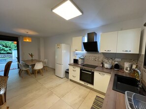 A compact kitchen with white cabinets, a refrigerator, a microwave, and a sink.