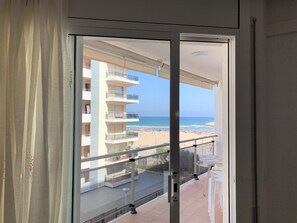 Un balcón con vista a la playa y un edificio de varios pisos.