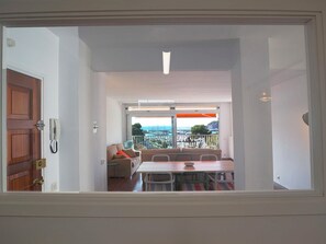 Ein Zimmer mit Balkon, einem Tisch, Stühlen, einer Couch und einem Telefon.