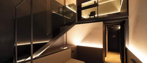 Un interior moderno con una escalera, un rincón de lectura con un libro y vistas al piso superior.