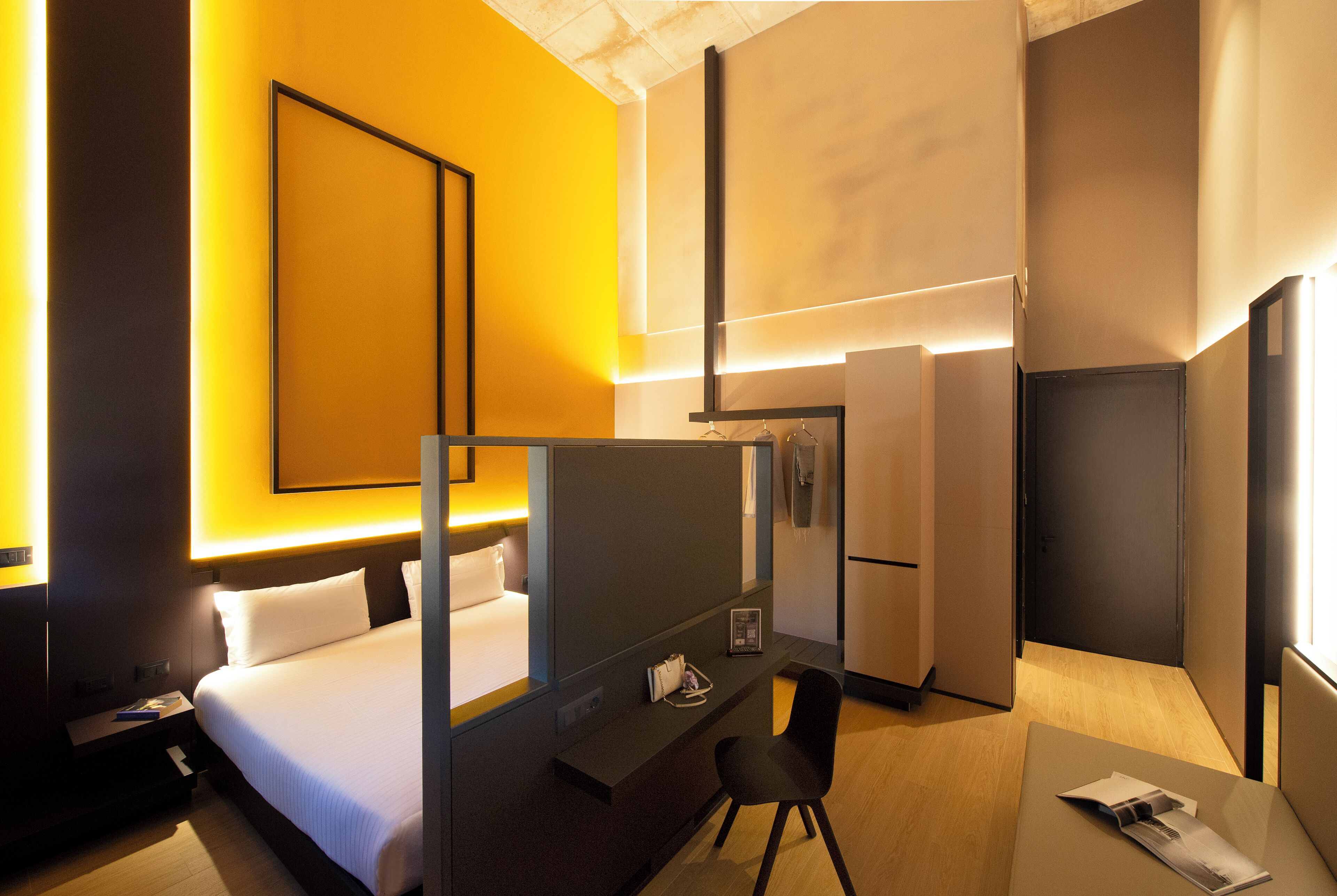 Una camera d'albergo con un letto, una scrivania, una sedia, un tavolino e uno specchio.