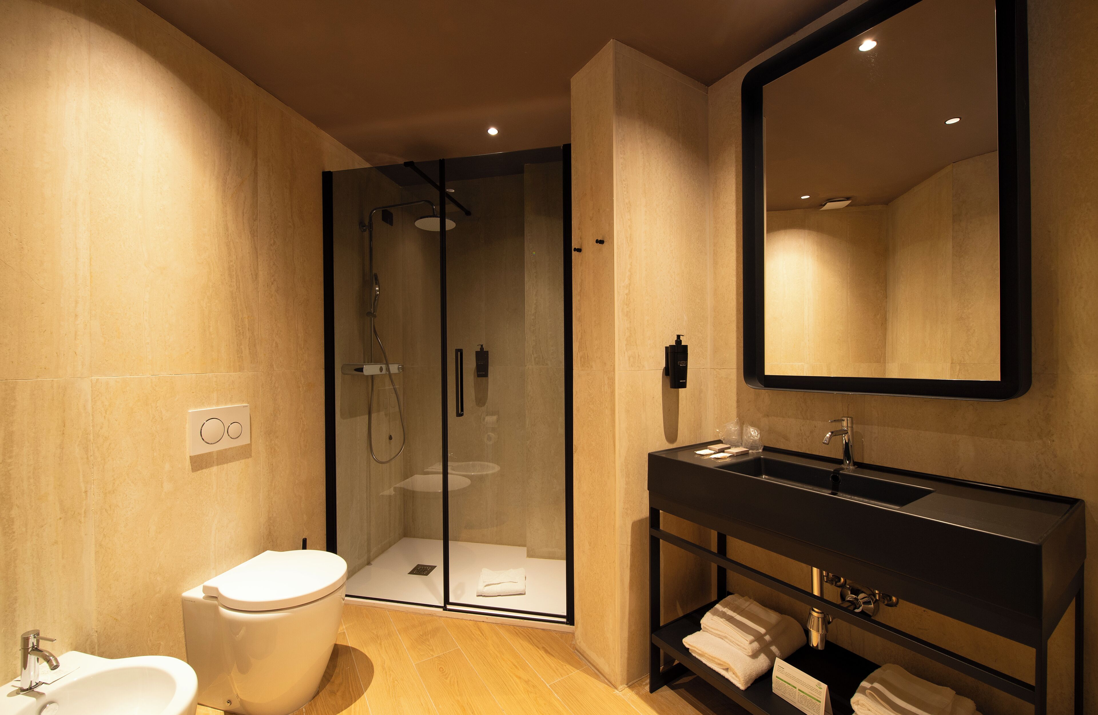 Un bagno moderno con cabina doccia in vetro, mobile lavabo nero e uno specchio grande.