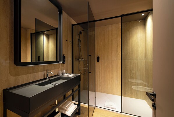A modern bathroom with a glass shower enclosure, a large mirror, and a black vanity with a sink.