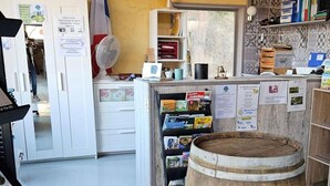 A rustic kitchen with wooden beams, a flag, a fan, and a barrel. - Chalet with terrace - 4 guests (Désaignes)