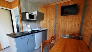 A compact kitchen with a microwave, a coffee maker, and a sink. There is a wooden dining table with chairs. - Chalet with terrace - 4 guests (Désaignes)