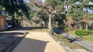 A residential street with a sidewalk, a wooden house, and a row of trees. - Chalet with terrace - 4 guests (Désaignes)