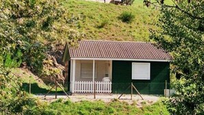 A small, single-story house with a tiled roof, a fenced porch, and a green exterior. - Chalet with terrace - 4 guests (Désaignes)