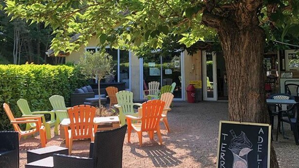 Outdoor seating with chairs and tables, a signboard, and a tree. - Chalet with terrace - 4 guests (Désaignes)