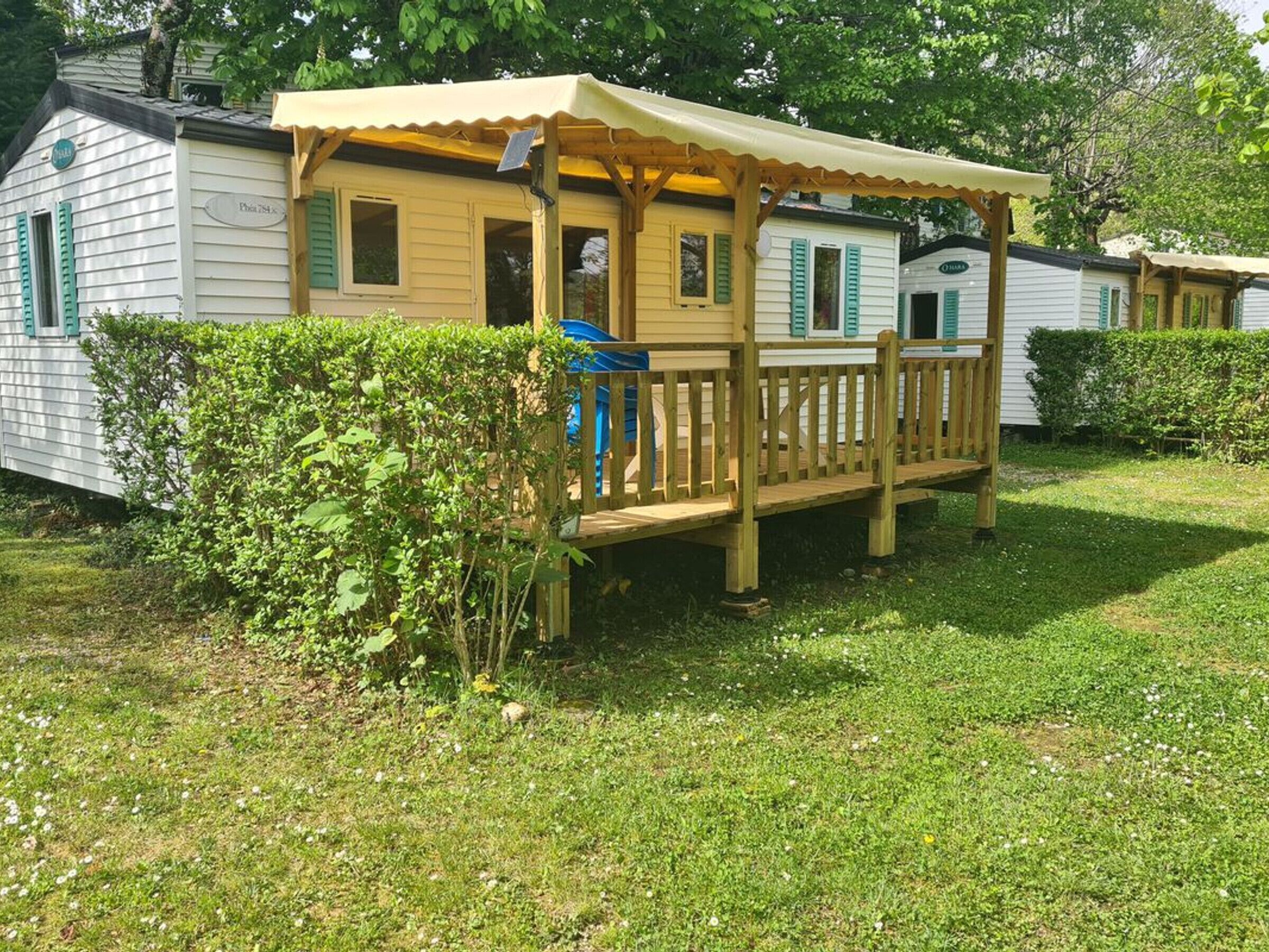 A mobile home with a wooden deck and a covered porch.