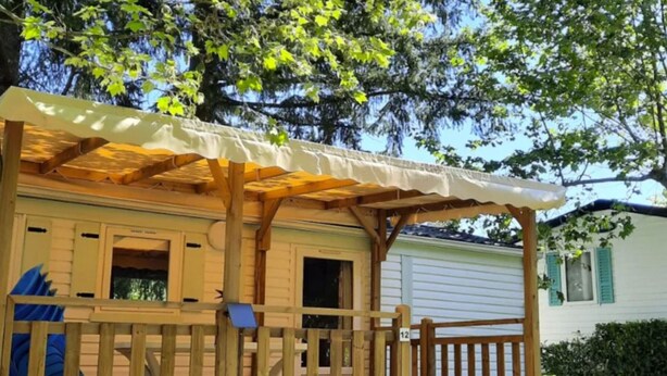 Une terrasse en bois avec un espace salon couvert et une petite table.