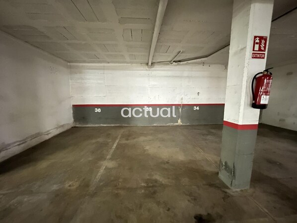 A parking garage with concrete floors and walls, marked parking spaces 36 and 34, and a fire extinguisher on a pillar. - Modern apartment 400m from beach with pool, WiFi, parking and terrace (Platja d'Aro)