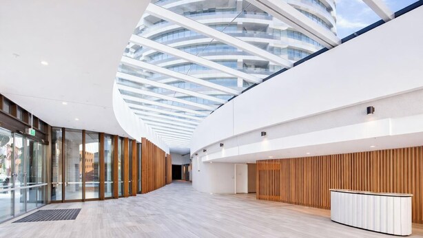 A modern building with a curved glass ceiling, wooden panel walls, and a reception desk. - MetaWiseBnB 1BR Sleep 3 Perfect for Easter Show W Parking (Sydney Olympic Park)