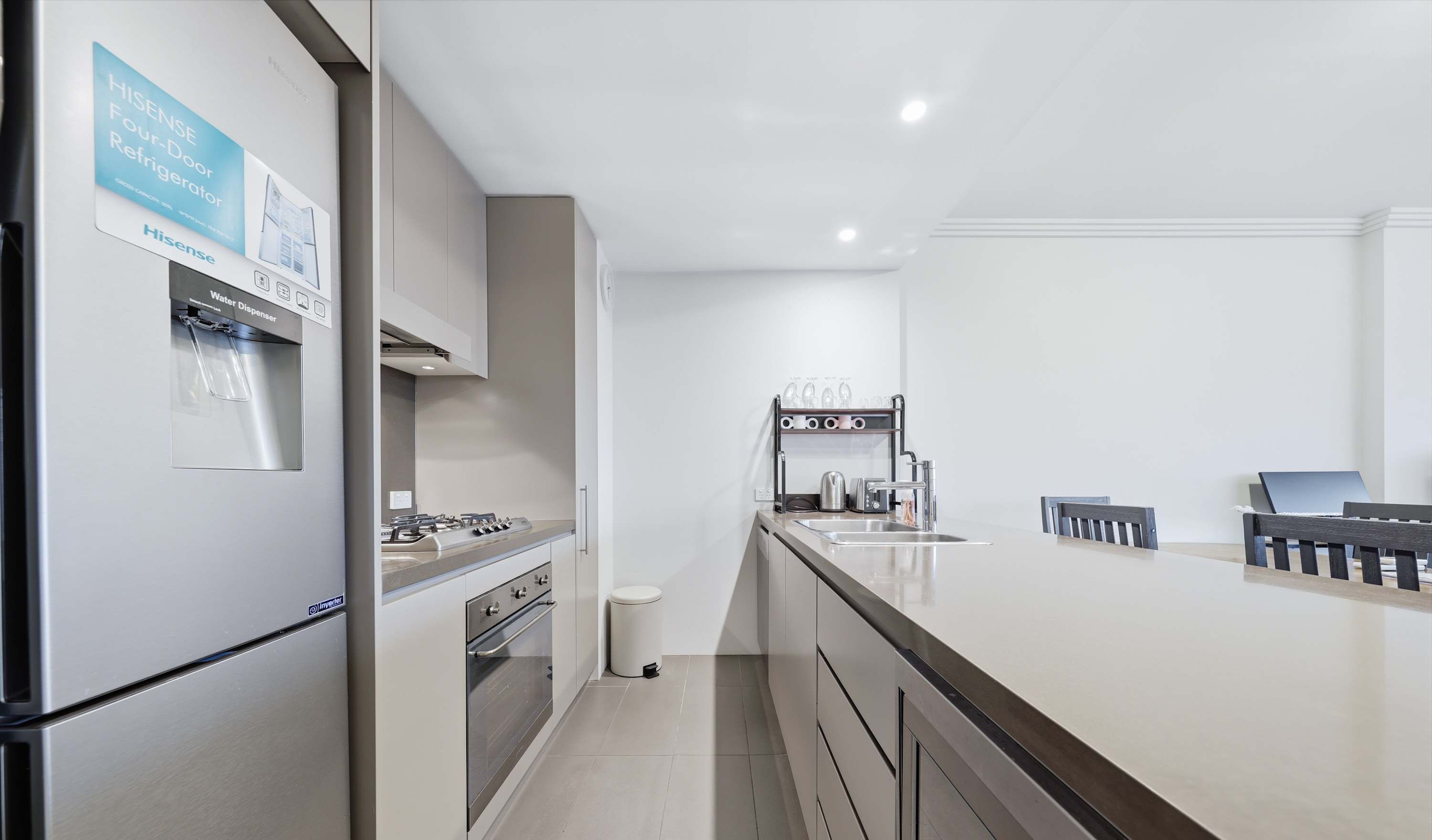 A modern kitchen with a stainless steel refrigerator, a gas stove, an oven, a water dispenser, and a sink with a stainless steel faucet.