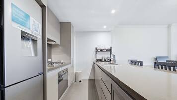 A modern kitchen with a stainless steel refrigerator, a gas stove, an oven, a water dispenser, and a sink with a stainless steel faucet.
