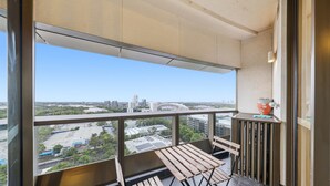 A balcony with a view of a cityscape, a wooden bench, and a small table with a vase. - MetaWiseBnB 1BR Sleep 3 Perfect for Easter Show W Parking (Sydney Olympic Park)