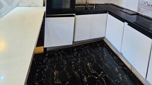 A modern kitchen with white cabinetry, a black countertop, a built-in oven, and a sink.