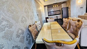 A dining area with a marble table, tufted chairs, and patterned wallpaper.