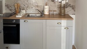 Una cocina compacta con salpicadero de mármol, lavavajillas integrado y encimera de madera.
