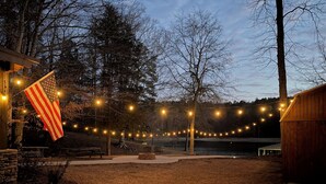 Een terras met lichtslingers, een vlag en een vuurkorf van steen.