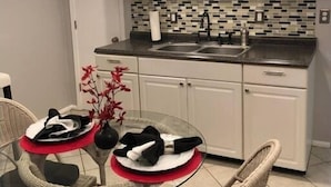 A modern kitchen with white cabinets, a black countertop, and a tiled backsplash. - Louisville's Central "Lilly Pad" (Louisville)