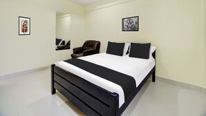 Ein modernes Schlafzimmer mit einem großen Bett, einem Sessel und zwei gerahmten Bildern an den Wänden.