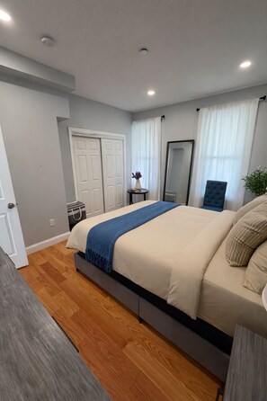 A bedroom with a bed, bedside table, mirror, and a chair. - Cozy 1-bedroom apartment in pleasant Nyack with AC (Nyack)