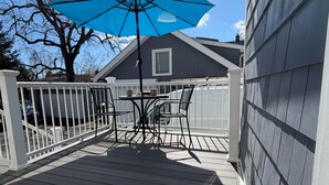 Une terrasse avec une table et des chaises, un parasol bleu, et une maison en arrière-plan.
