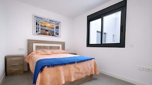 A bedroom with a bed, a nightstand, a window, and a wall-mounted picture. - Marinsa Beach - Penthouse (Torrox)